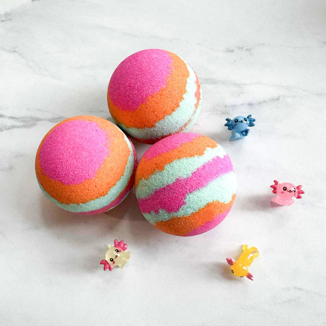 Three colorful bath bombs with pink, orange, and mint green swirls arranged on a white marble surface, with small toy animals placed around them.
Pop It Open & Pull Apart Mold Free Bath Toys	Jul 20, 2026
Sunday's Best  Axolotl Surprise Bath Bomb