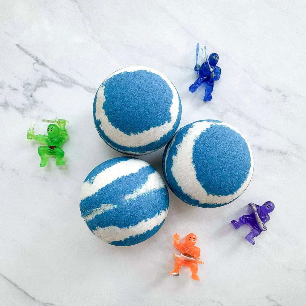 Three round bath bombs with a blue and white marbled pattern are arranged on a white marble surface, surrounded by five small translucent action figure toys in green, blue, purple, and orange.
Pop It Open & Pull Apart Mold Free Bath Toys	Jul 20, 2026
https://thelittlebooshop.com/products/sundays-best-hidden-ninja-bath-bomb
Sunday's Best Hidden Ninja Bath Bomb