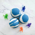 Three round bath bombs with a blue and white marbled pattern are arranged on a white marble surface, surrounded by five small translucent action figure toys in green, blue, purple, and orange.
Pop It Open & Pull Apart Mold Free Bath Toys	Jul 20, 2026
https://thelittlebooshop.com/products/sundays-best-hidden-ninja-bath-bomb
Sunday's Best Hidden Ninja Bath Bomb