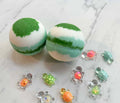 Two round bath bombs with green and white marbled patterns are displayed on a light marble surface, surrounded by small decorative turtle charms in various colors.
Pop It Open & Pull Apart Mold Free Bath Toys	Jul 20, 2026
https://thelittlebooshop.com/products/sundays-best-hidden-ninja-bath-bomb
Sunday's Best Treasure Turtle Bath Bomb