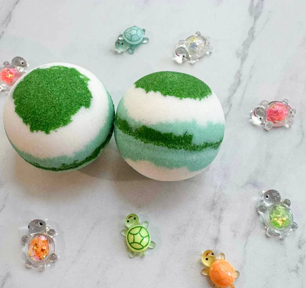 Two spherical bath bombs with a green and white marbled pattern are displayed on a light gray marble surface, surrounded by small decorative turtle charms.
Pop It Open & Pull Apart Mold Free Bath Toys	Jul 20, 2026
https://thelittlebooshop.com/products/sundays-best-hidden-ninja-bath-bomb
Sunday's Best Treasure Turtle Bath Bomb